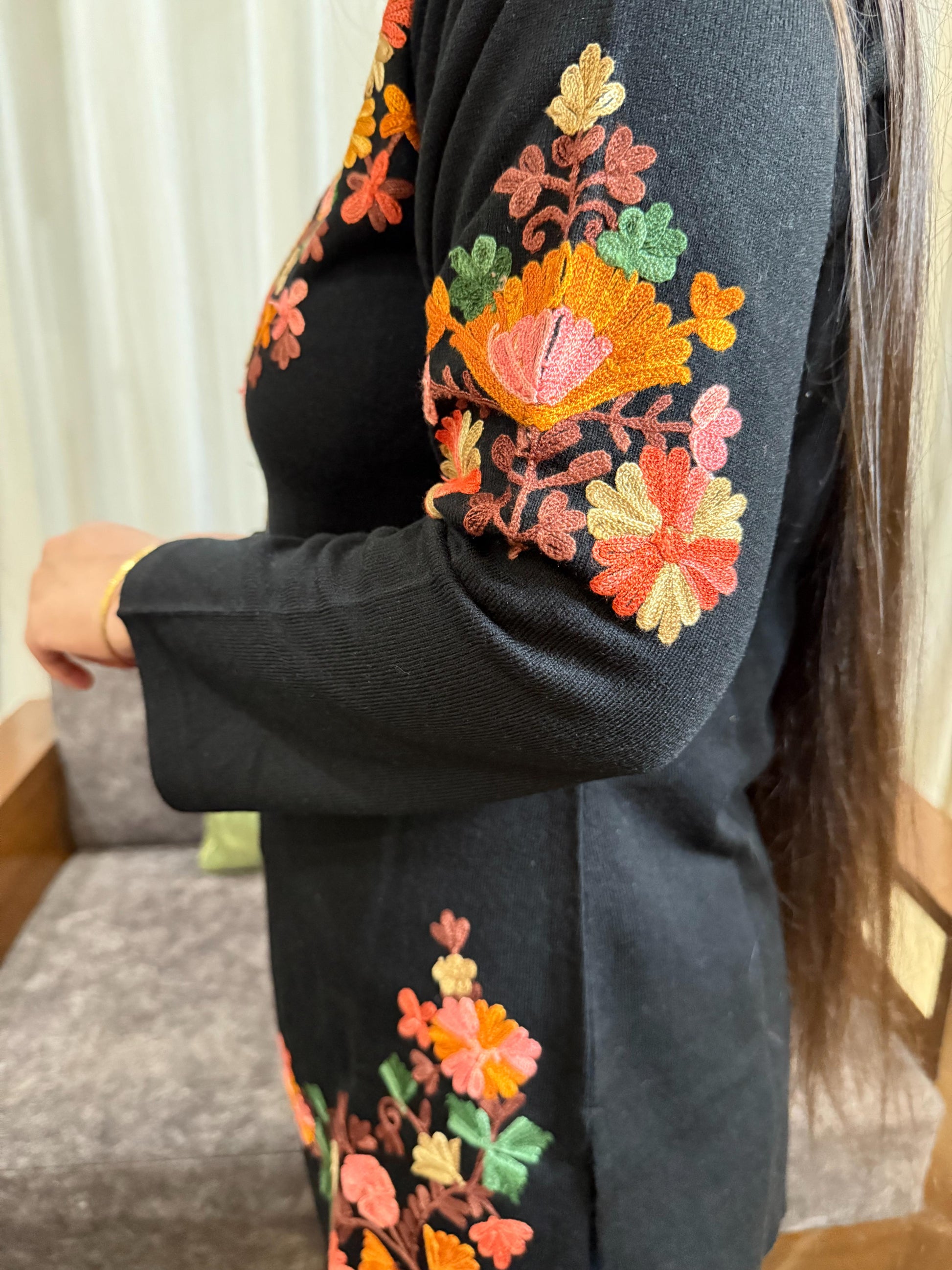 Black garment with colorful floral embroidery on a neutral background GulmoharBlackEmbroideredKashmiriWoollenKurti5