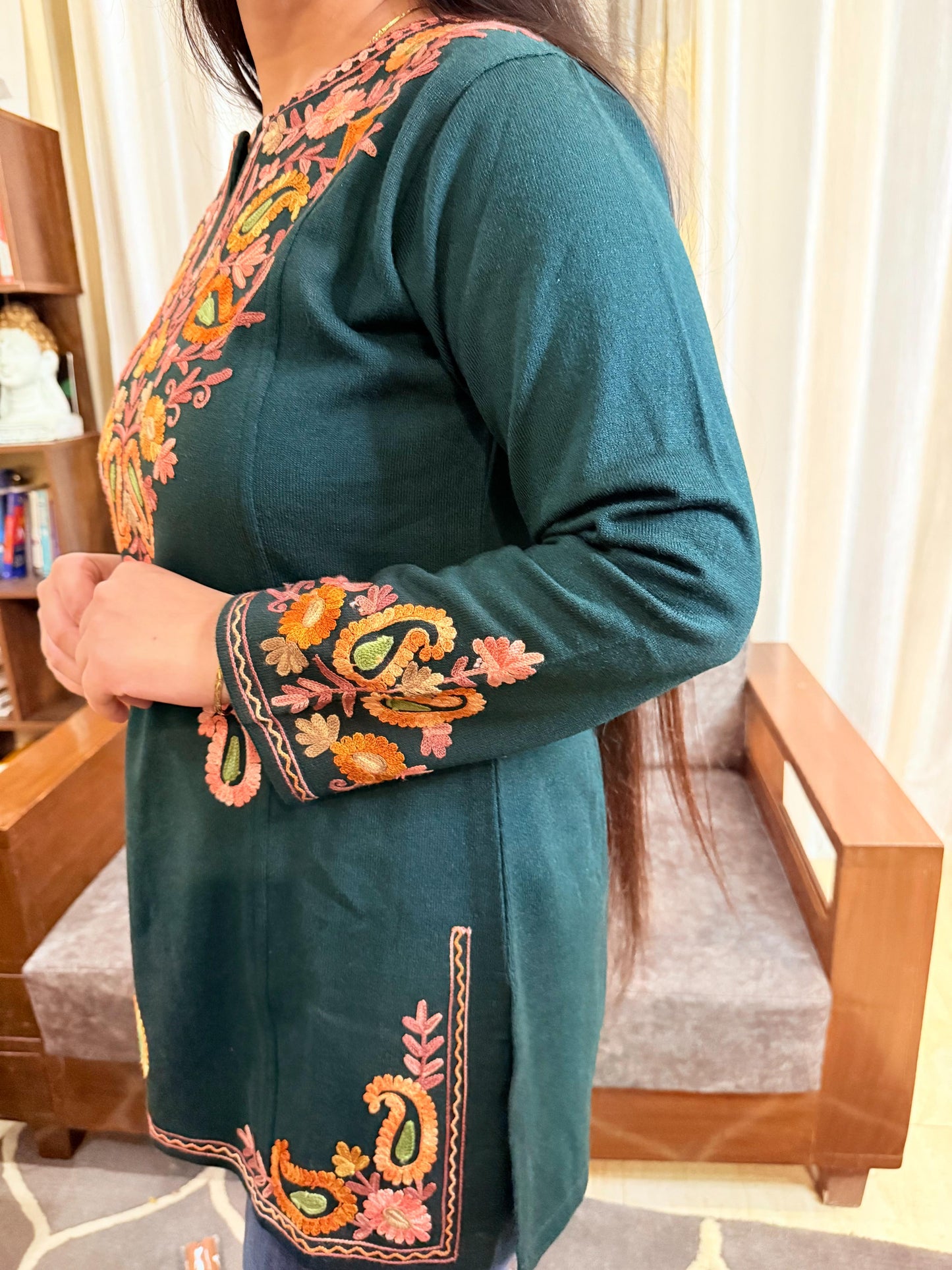 Teal embroidered dress worn by a person in a room with wooden furniture. GulmoharTealEmbroideredKashmiriWoollenKurti3