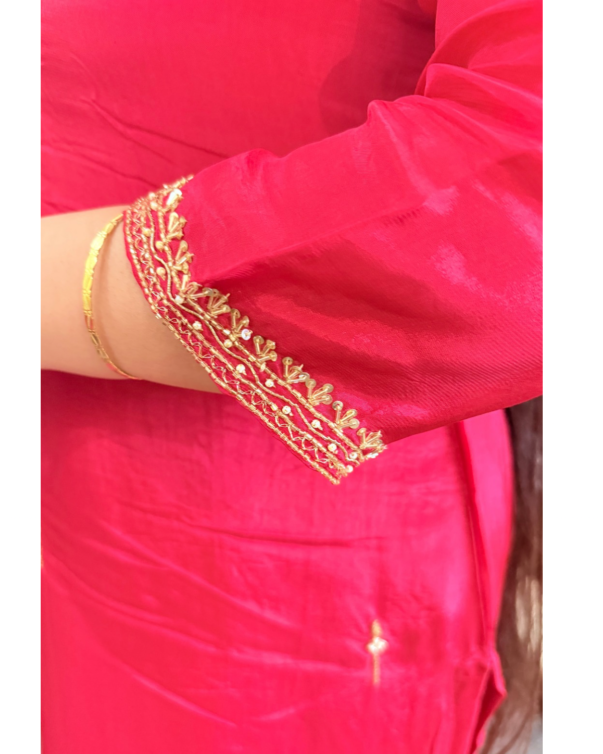 Close-up of a red garment with gold embroidery on a plain background.ZYRAFESTIVESUITSETTHEMKMAAN