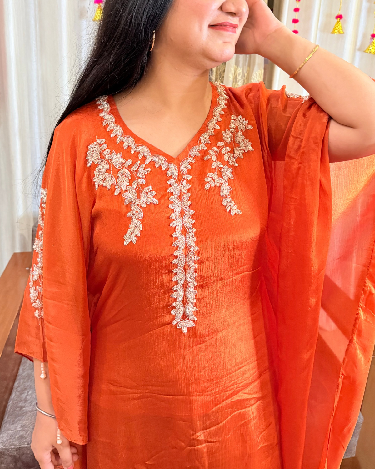 Orange traditional outfit with white embroidery worn by a person. saffron shine festive kaftan set